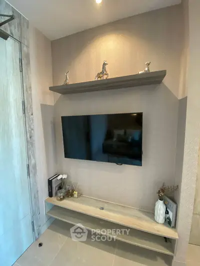 Modern living room with mounted TV and decorative shelves in stylish apartment.