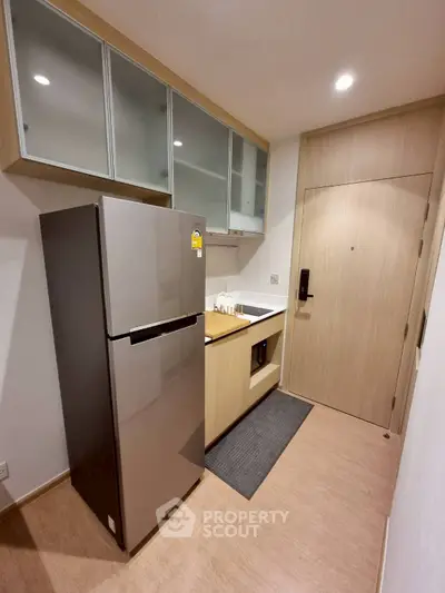 Modern kitchen with sleek cabinets and stainless steel fridge in cozy apartment.