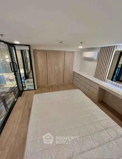 Modern bedroom with wooden flooring, built-in wardrobe, and large windows for natural light.