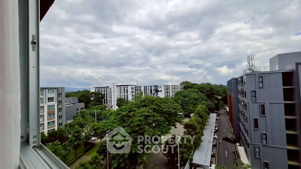 Stunning urban view from a high-rise apartment window showcasing modern buildings and lush greenery.