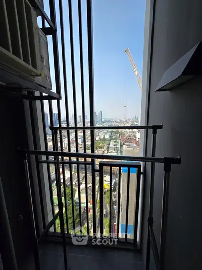 Stunning city view from a high-rise balcony with modern railing and construction crane in the distance.