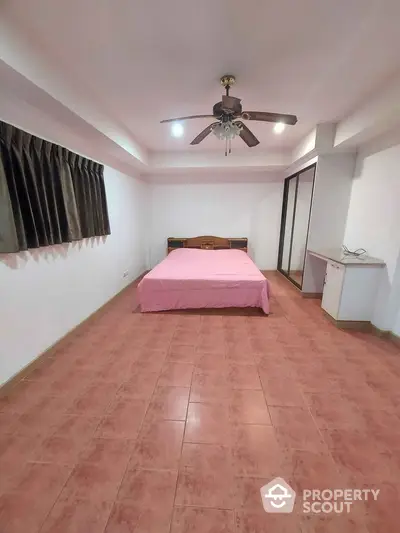 Spacious bedroom with terracotta tiled flooring, ceiling fan, and large wardrobe, offering a blank canvas for personalization.