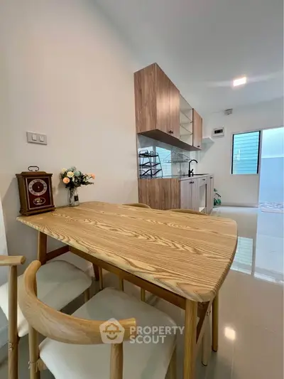 Modern kitchen with wooden dining table and sleek cabinetry in a bright, airy space.