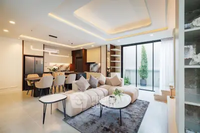 Luxurious open-plan living room with modern decor and spacious dining area, featuring elegant lighting and large windows.