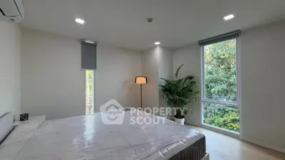 Modern bedroom with large windows and lush greenery view