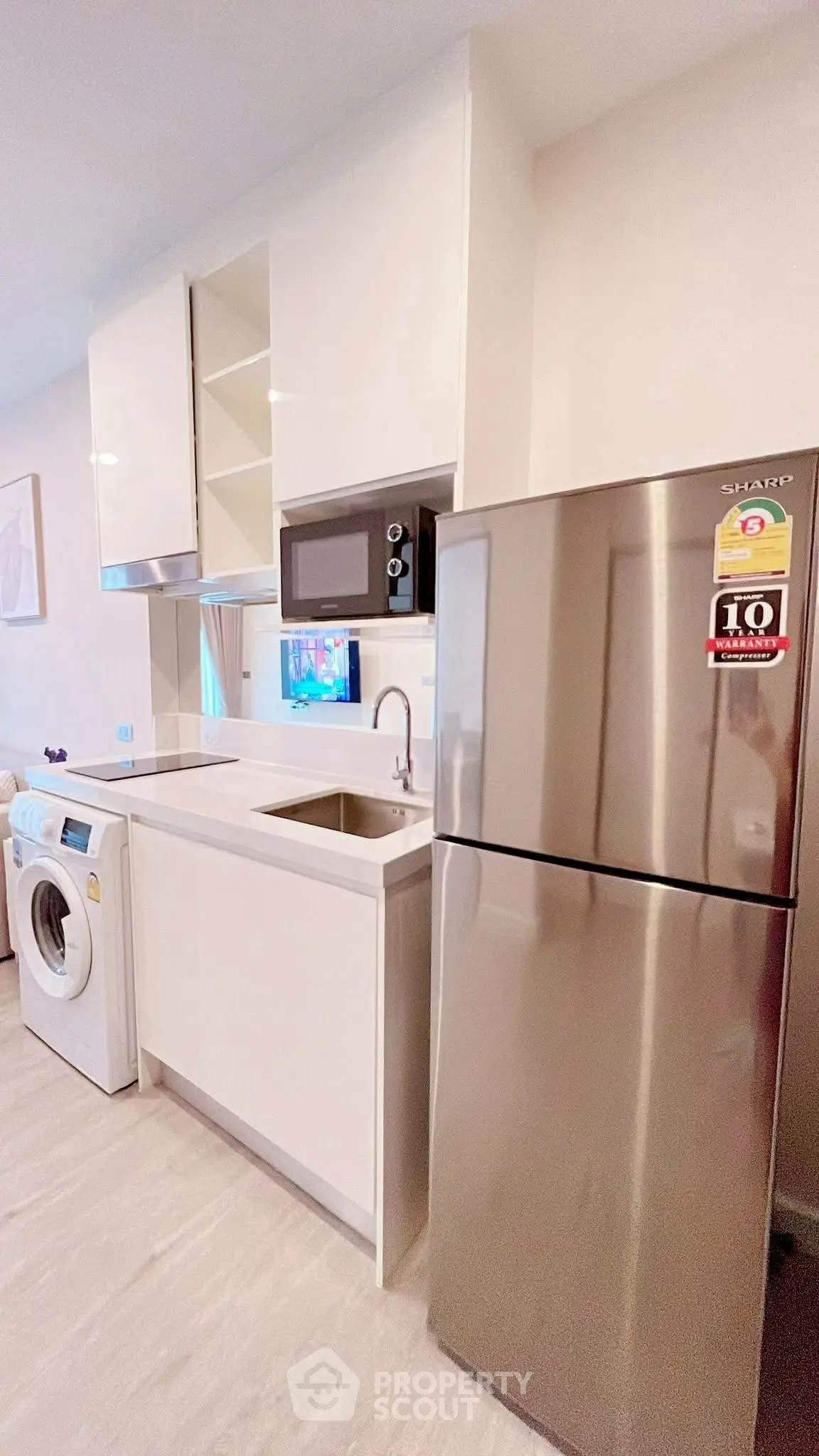 Modern kitchen with sleek appliances including fridge, microwave, and washing machine.