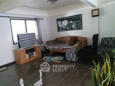 Spacious living room with tiled floor, cozy seating, and natural light from large window.