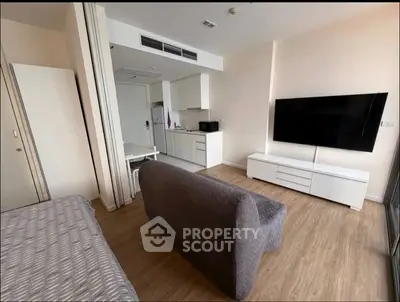 Modern studio apartment with sleek kitchen and large wall-mounted TV