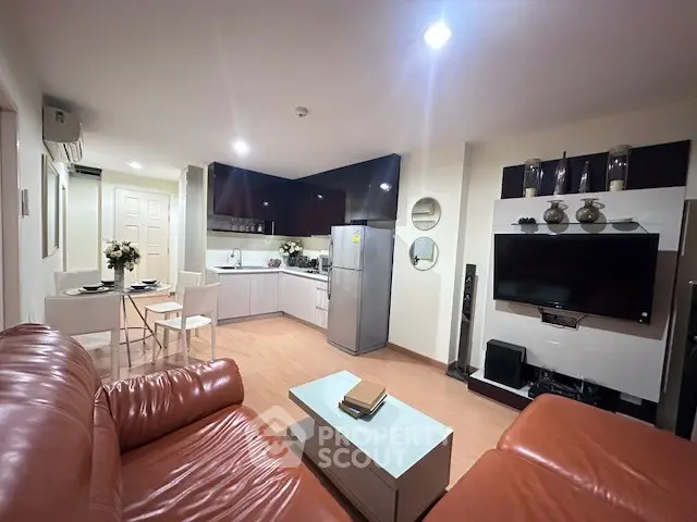 Modern living room with open kitchen, leather sofas, and sleek decor in a cozy apartment.