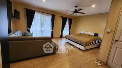 Spacious bedroom with modern decor, featuring a cozy sofa and large windows for natural light.