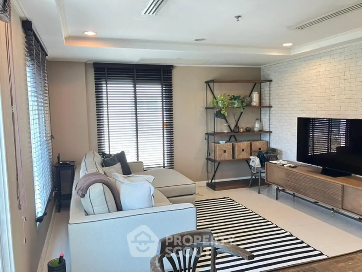 Modern living room with stylish decor, large windows, and cozy seating area.