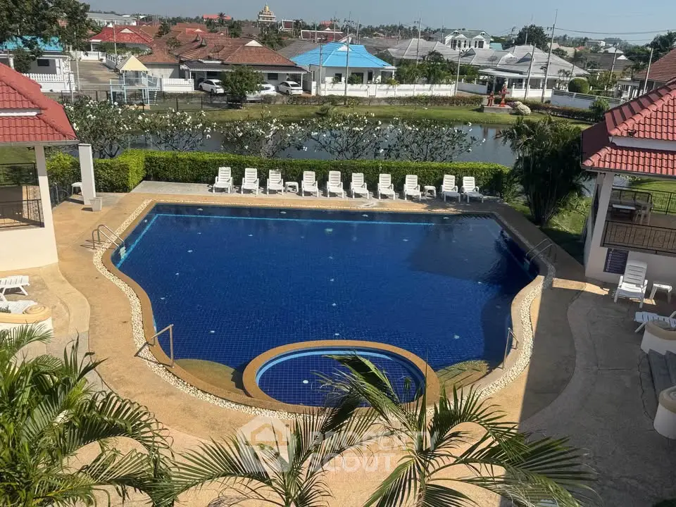 Luxurious residential pool with sun loungers and scenic view, perfect for relaxation.