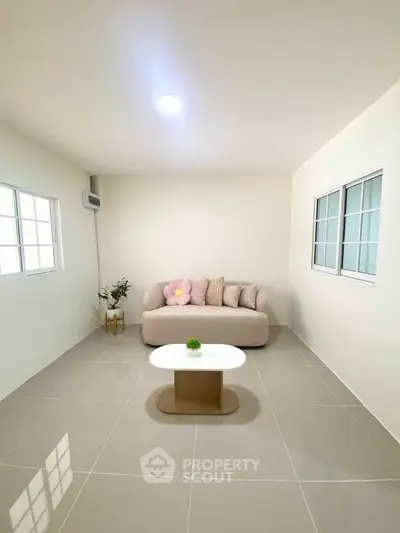 Minimalist living room with modern sofa and coffee table, bright natural light through windows.