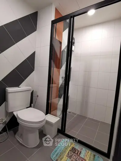 Modern bathroom with stylish black and white tiles and glass shower enclosure.