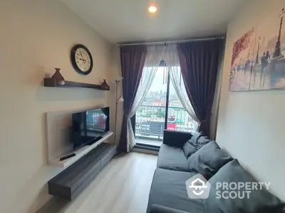 Cozy living room with modern furnishings, large windows leading to a balcony with a view, creating a bright and inviting space.