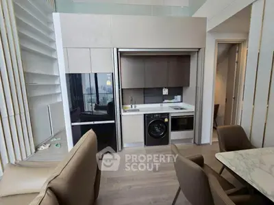 Modern open-layout kitchen with sleek appliances and dining area in stylish apartment.