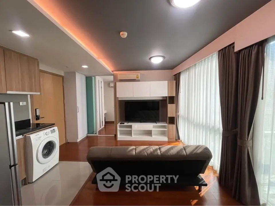 Modern living room with sleek design, featuring a washing machine and large windows for natural light.