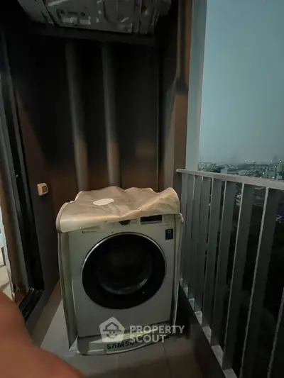 Compact balcony with washing machine and city view, ideal for urban living convenience.