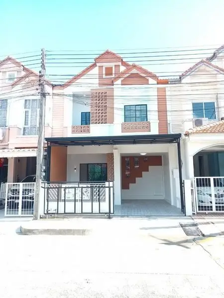 Charming townhouse exterior with modern design and gated parking area.
