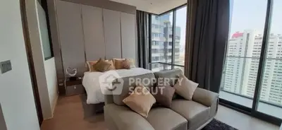 Luxurious bedroom with floor-to-ceiling windows and city view, featuring elegant decor and cozy seating area.