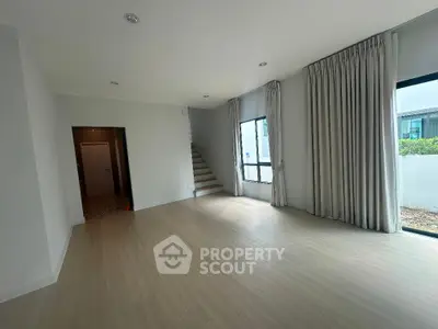 Spacious living room with large windows and staircase in modern home