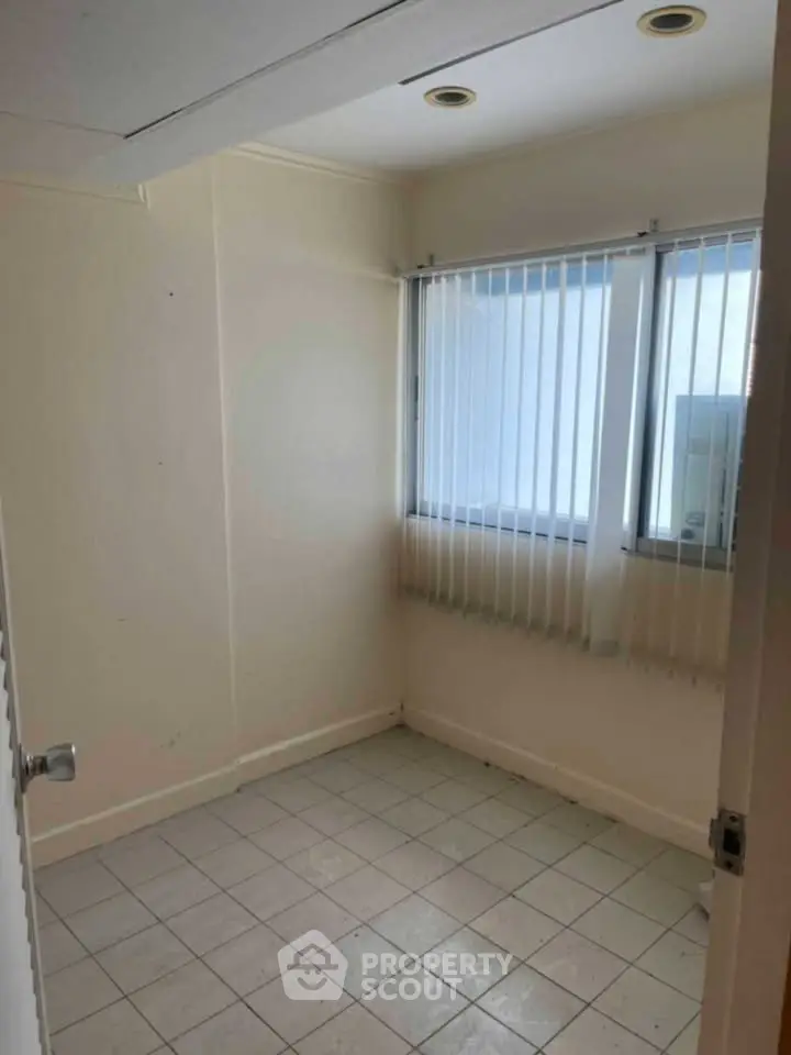 Compact room with tiled floor and vertical blinds, ideal for small office or storage.