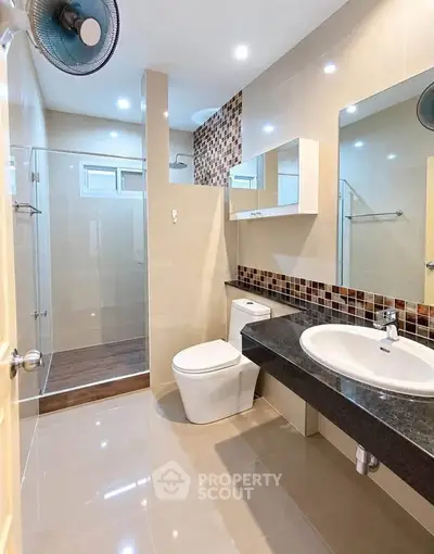 Modern bathroom with sleek design, featuring a glass shower enclosure and stylish vanity.