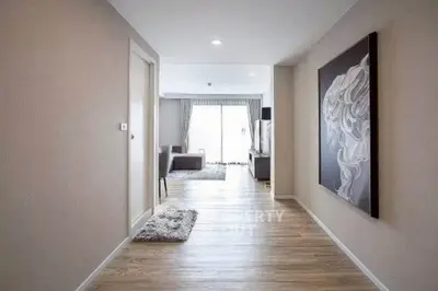 Spacious modern hallway leading to a bright living room with elegant decor and large windows.