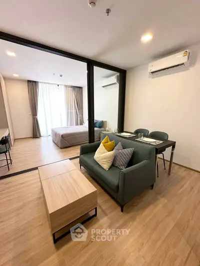 Modern open-plan living room with cozy seating and dining area, featuring sleek wooden flooring and stylish decor.