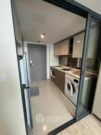 Modern kitchen with sleek appliances and washing machine in compact layout