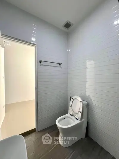 Modern bathroom with sleek white tiles and contemporary toilet design.