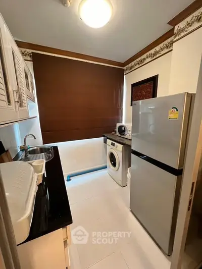 Modern kitchen with washing machine and fridge in compact layout