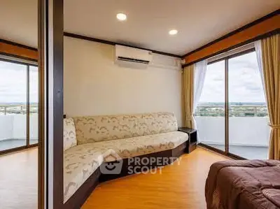 Spacious living room with modern sofa and balcony view in a high-rise apartment.