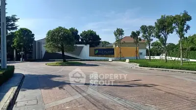 Modern residential entrance with lush greenery and clear blue sky.