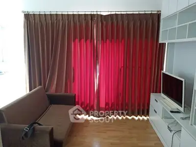Cozy living room with modern sofa and entertainment unit, featuring elegant floor-to-ceiling curtains.