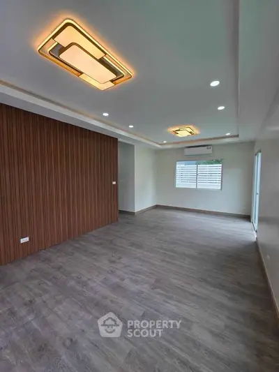 Spacious modern living room with stylish ceiling lights and wooden flooring