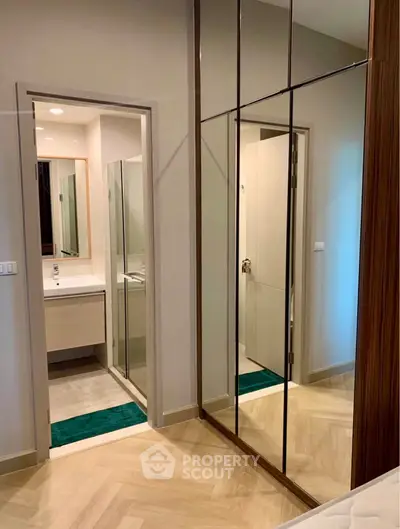 Modern bedroom with mirrored closet doors and view into sleek bathroom