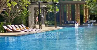 Luxurious outdoor pool area with sun loungers and lush greenery, perfect for relaxation and leisure.