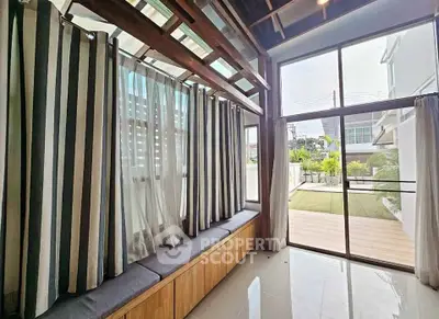 Spacious sunlit room with large windows and garden view, perfect for relaxation.