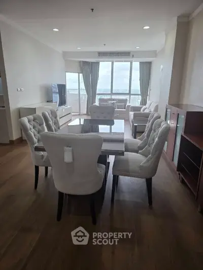 Spacious living room with elegant dining set and panoramic window view.