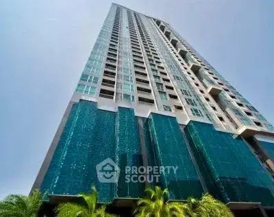 Stunning modern high-rise building with sleek glass facade and lush greenery at the base.
