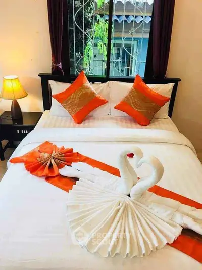 Cozy bedroom with elegant swan towel art and vibrant orange accents.