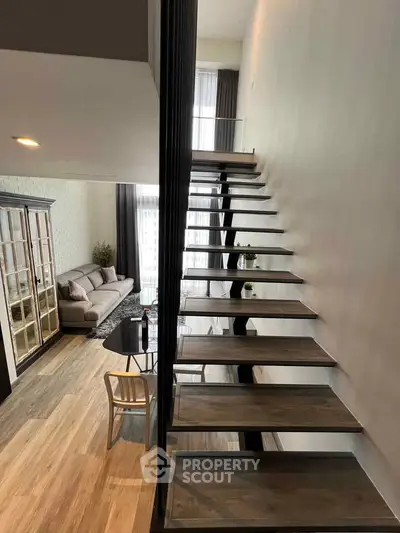 Modern duplex interior with stylish staircase and cozy living area, featuring elegant decor and ample natural light.