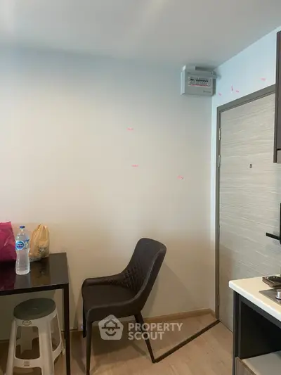 Modern apartment interior with sleek chair and dining area, showcasing minimalist design and functionality.