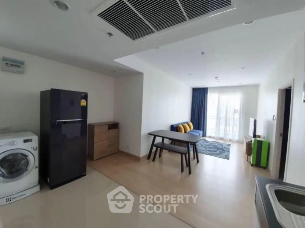 Modern open-plan living room with kitchen, featuring sleek appliances and stylish decor.