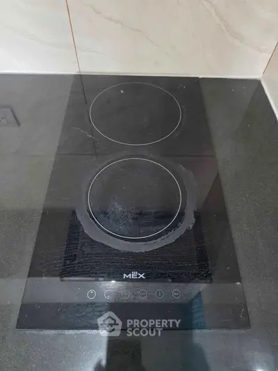 Modern kitchen with sleek black glass cooktop and minimalist design.