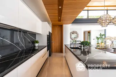 Luxurious modern kitchen with sleek black marble countertops, high-end appliances, and a striking wooden ceiling, perfect for culinary enthusiasts.