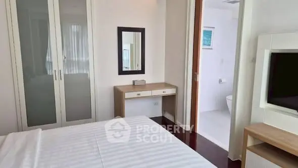 Modern bedroom with sleek furniture and ensuite bathroom in luxury apartment.