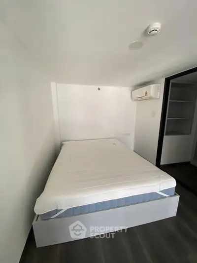 Modern minimalist bedroom with sleek design and air conditioning unit.