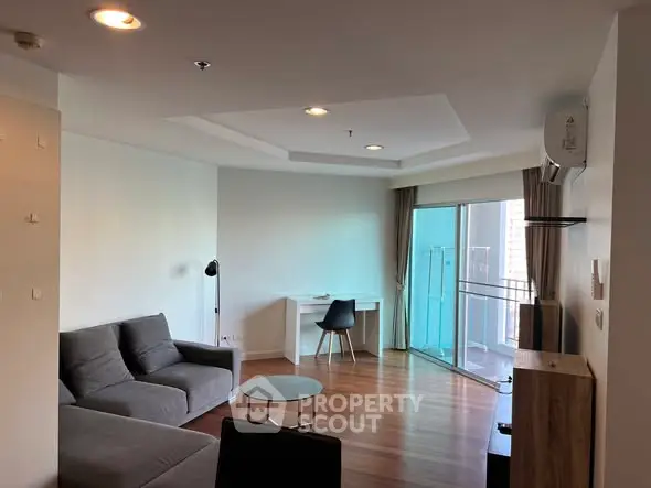 Modern living room with balcony, featuring sleek furniture and wooden flooring.